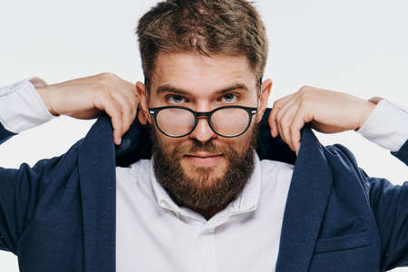 Business man with glasses, businessman straightens collar, business man on light background portraitの写真素材