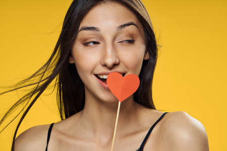 Holiday, woman smiling, woman with heart on stick woman on yellow background.の写真素材