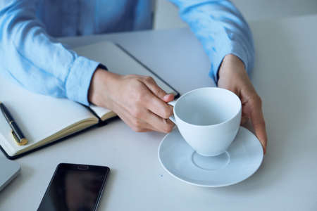 Business woman with a mug, business woman, notepad, phone, pen.