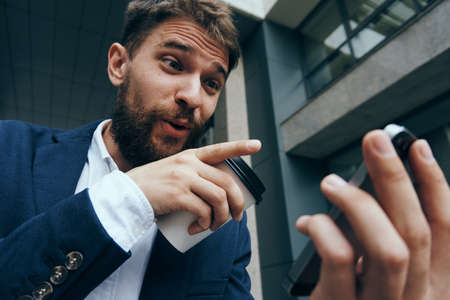 Surprised businessman, businessman looking into the phone, business man with a coffee mug.の写真素材
