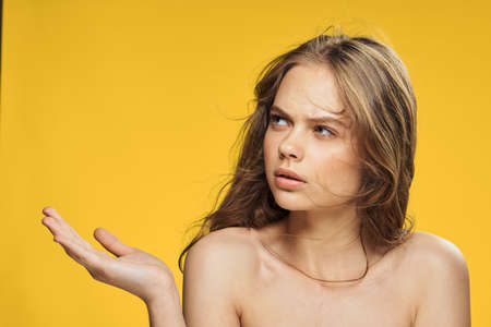 Woman shows on empty space, woman on yellow background portrait.の写真素材