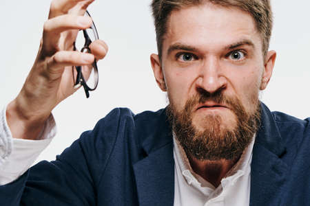 Unhappy businessman, businessman holding glasses, businessman on light background portrait.