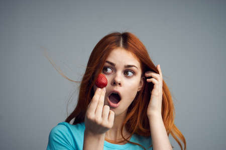 Strawberry, woman surprised, woman with strawberry, woman holding strawberries on gray background.の写真素材
