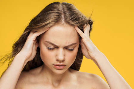 Headache, migraine, health, girl on a yellow background, the girl holds her head.の写真素材