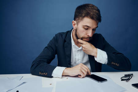 Business man, business man looking into the phone, man on a blue background, business man at the deskの写真素材