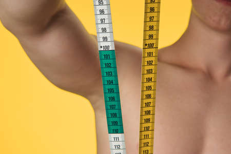 Man, losing weight, man holding a tape to measure his waist, a man on a yellow background.の写真素材