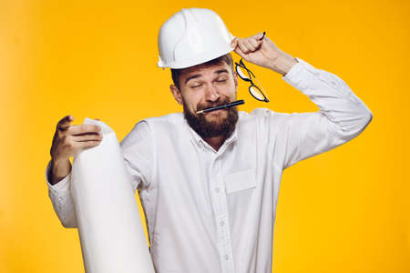 Engineer, builder on a yellow background, an engineer holds glasses, a builder holds a drawing.の写真素材