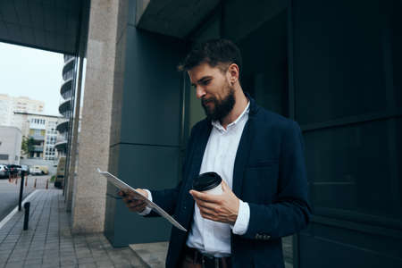 Business man with a beard on the street looking at documents, business man drinking coffee.の写真素材