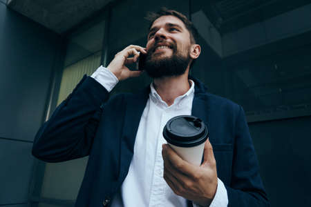 Businessman with a beard talking on the phone in the street, busy man in the city, coffee.の写真素材