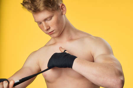 Athlete, red hair, elastic bandage, guy on a yellow background, fitness, sports.の写真素材