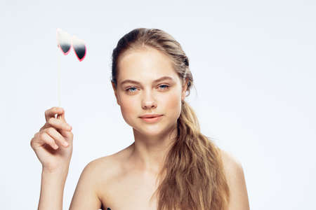 Paper accessory, accessory for parties, woman with paper glasses on a stick on a light background.の写真素材
