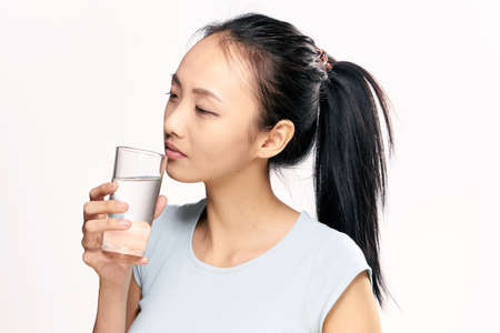 Water, a glass of water, a woman with a glass of water, a woman on a light background.の写真素材