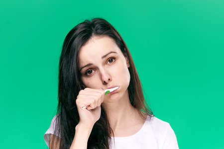 Healthy teeth, a woman brushes teeth, a toothbrush, dental care, oral hygiene, a woman on a green background.の写真素材