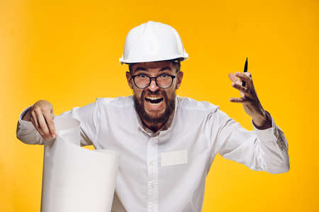 Engineer in helmet, construction helmet, engineer evil, engineer with blueprint on yellow background.の写真素材