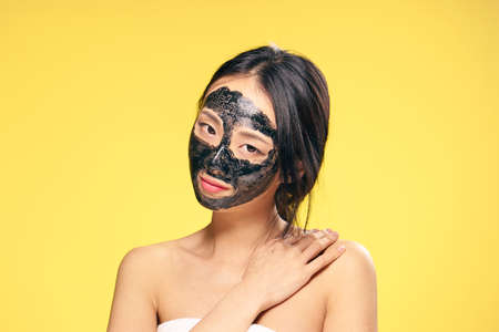 Facial skin care, skin problem, cleansing mask, woman in cosmetic mask, woman on yellow background.の写真素材