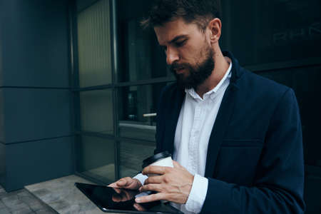 Businessman on the street in the city holds a phone, busy man.の写真素材