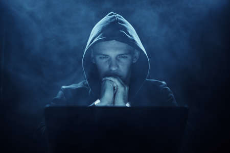 Hacker, programmer, laptop, darkness, man looks at laptop, program, matrix.の写真素材