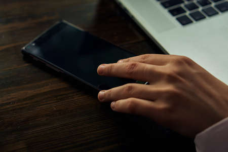 Office, work, hand holds phone, laptop, desktop.の写真素材