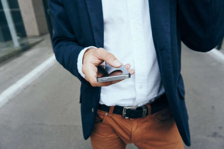 Businessman holding a phone, hands, street, formal suit, manの写真素材