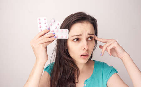 Woman sick, pain, pills, woman with pills, woman on a light background.の写真素材
