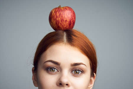 Woman with apple on her head, woman with apple, healthy eating, apple, diet, woman on gray background.の写真素材