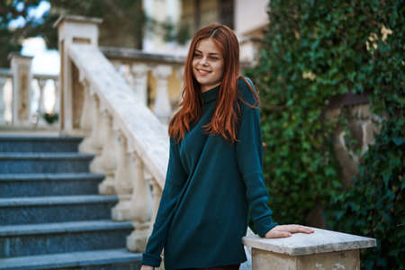 Woman leaning on a railing, woman on a wall background, woman background.の写真素材