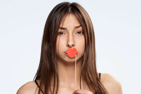 Holiday, woman with lips on stick, paper lips, woman on c light background, carnival cardboard mask.