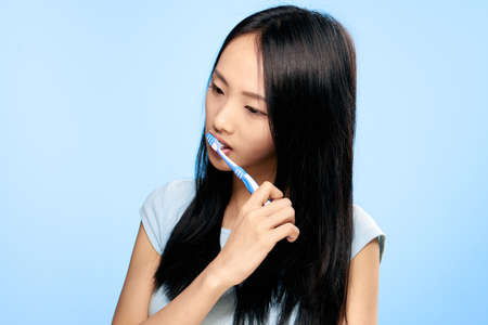 Woman brushing her teeth, woman with toothbrush, dental care, oral hygiene, woman on blue background.の写真素材