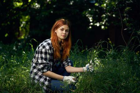 Woman with mower, woman in summer garden, gardener, woman in working gloves.の写真素材
