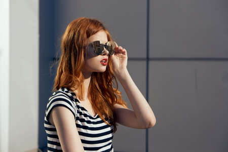 Young beautiful woman outdoors in sunglasses, style, fashion, red hair, red lips.の写真素材