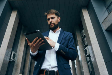Businessman with a beard holding a tablet on the street, work, office, city.の写真素材