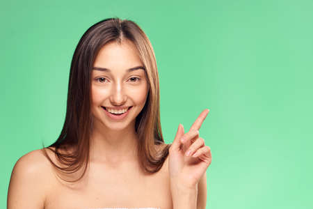 Woman shows on empty space on a green background, smile, emotions.の写真素材