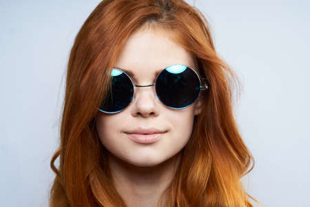 Portrait, fashion, style, young beautiful woman with red hair on white isolated background in sunglasses.の写真素材