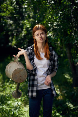 Emotions, woman in the garden holds a watering can, gardener, summer, season.の写真素材