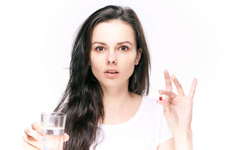 Young woman on white isolated background holds a pill, capsule, pharmacy, formateutics.の写真素材