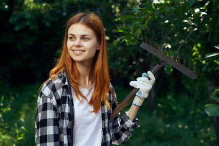 Gardener, young beautiful woman holding a rake in the garden.の写真素材