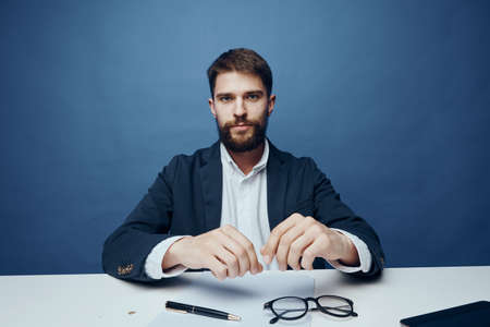 Business man at the desk in the office holds a pen.の写真素材