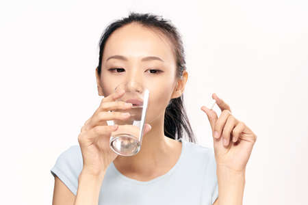 Young woman on white isolated background holds a pill, capsule, pharmacy, formateutics,Asian.の写真素材