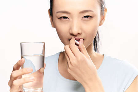 Pharmacy, pharmacy, woman on white isolated background holds a pill, capsule, asian.の写真素材