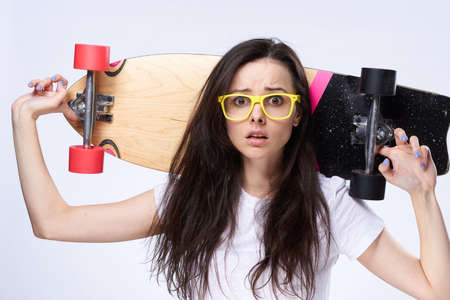Woman on white isolated background with glasses holds a long board.の写真素材