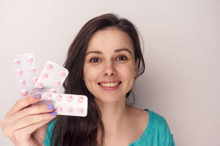 Young woman on a white background holds a pack of pills, pharmaceuticals.の写真素材