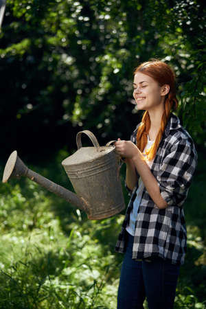 A woman in the garden holds a watering can, a gardener, summer.の写真素材