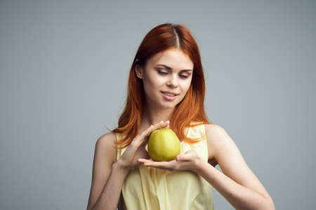 Young beautiful woman on a gray background holds an apple, fruit, diet.の写真素材