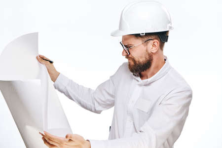 Engineer with a beard on a white isolated background holds a drawing.の写真素材