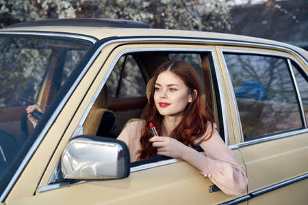 Beautiful young woman with red hair driving a car.の写真素材