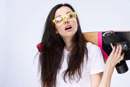 Young beautiful girl on white isolated background holds a long board.