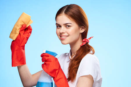 Young woman on a blue background, cleaning, rubber gloves, housework.