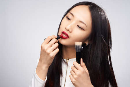 Asian woman on white background makes makeup.の写真素材