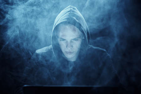 Hacker in a smoggy background, hacker in a hood on a dark background.の写真素材
