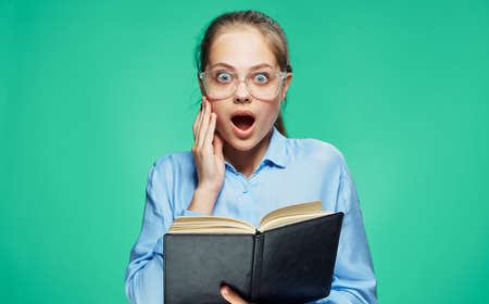Young beautiful woman in glasses on a green background holds a book.の写真素材